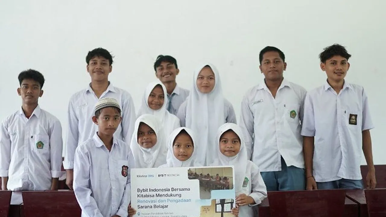 Students in white uniforms pose with a sign supporting classroom learning facilities.