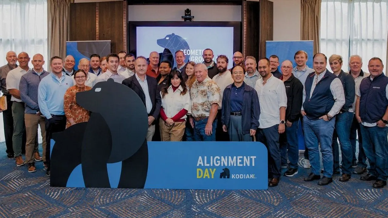 The Kodiak commercial team behind an Alignment Day sign featuring a large bear silhouette.