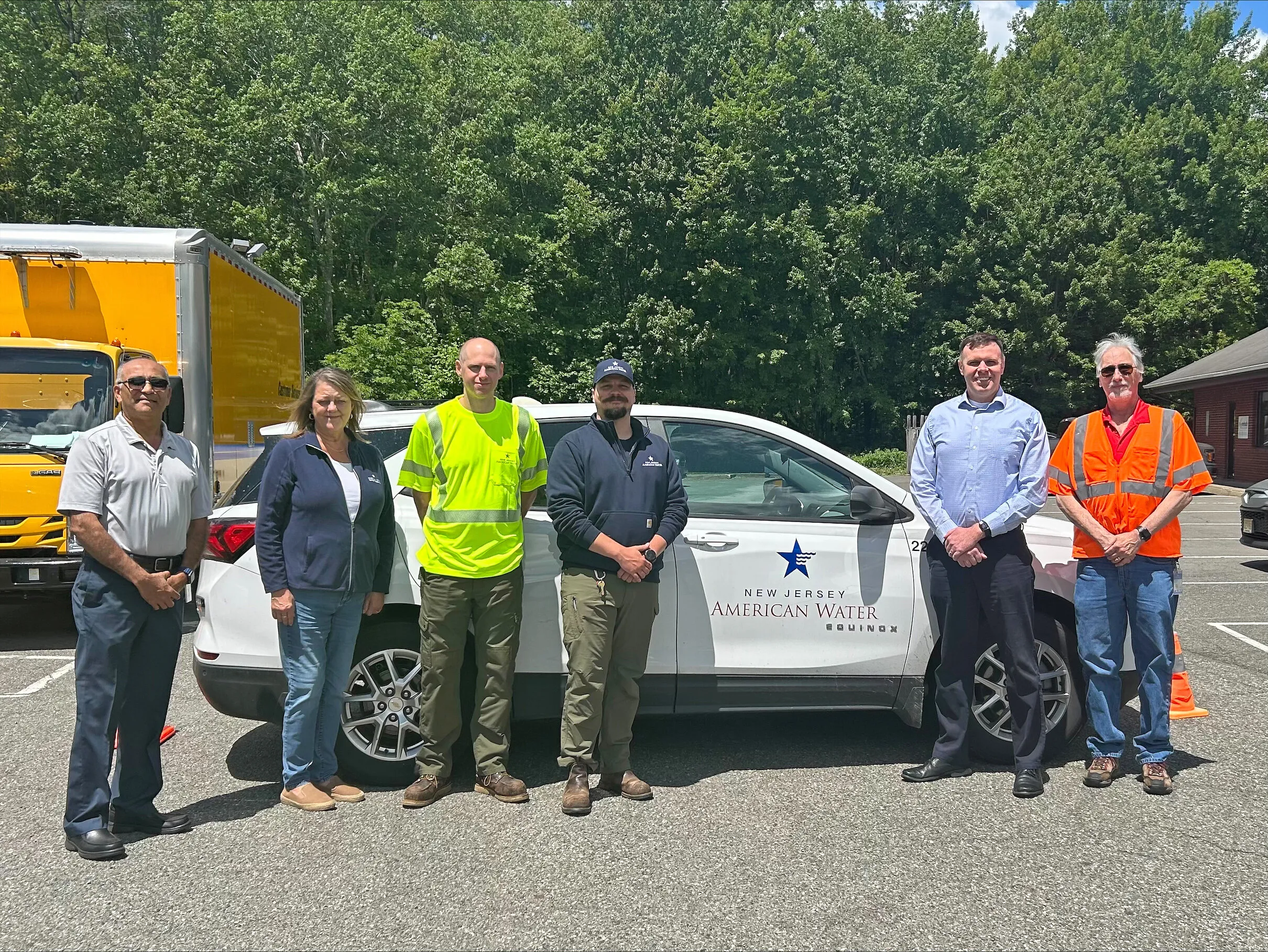 Six members of New Jersey American Water's new Montague Operations Team stand beside a company SUV and a yellow truck.
