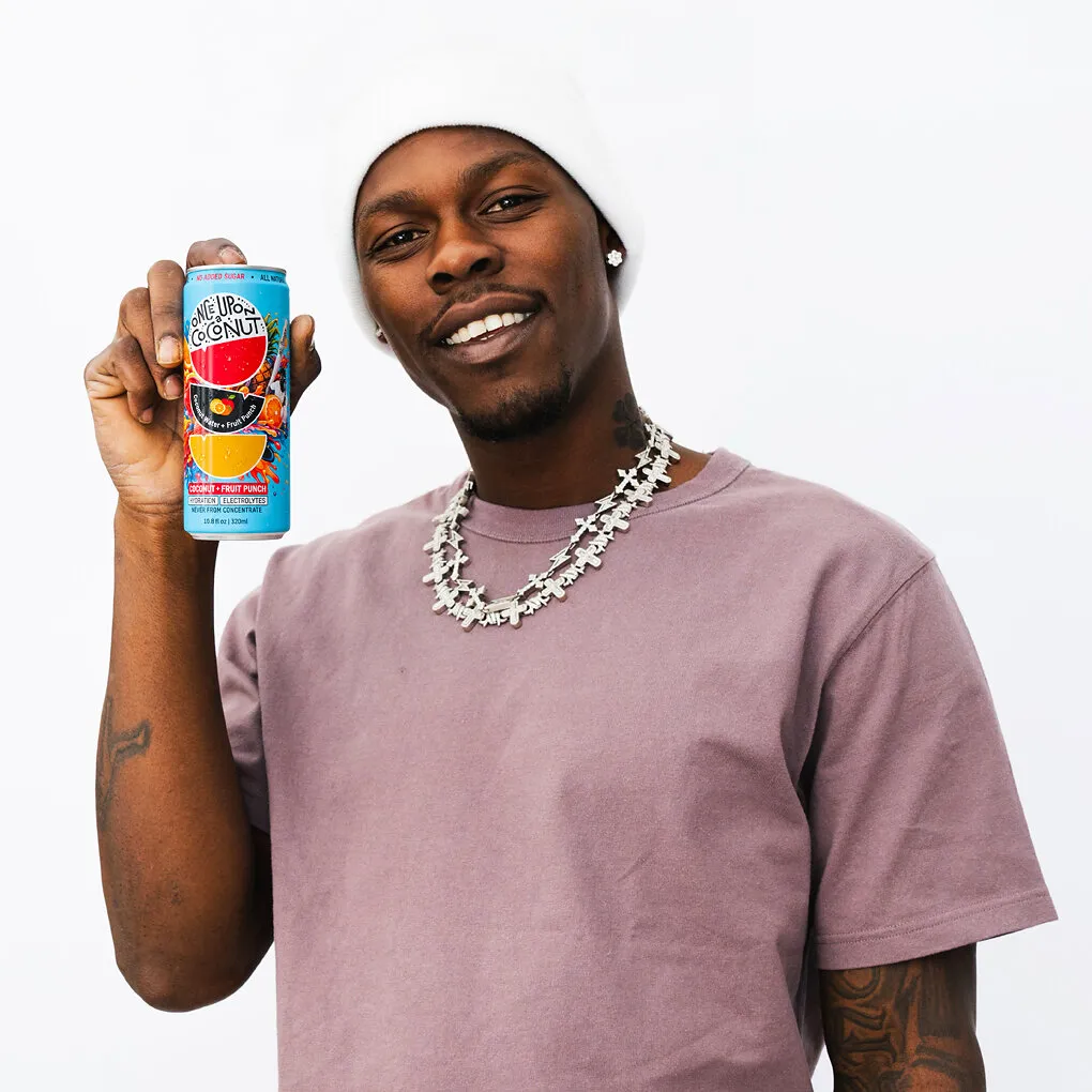 A person holds a can of One Up Coconut fruit punch electrolyte drink.