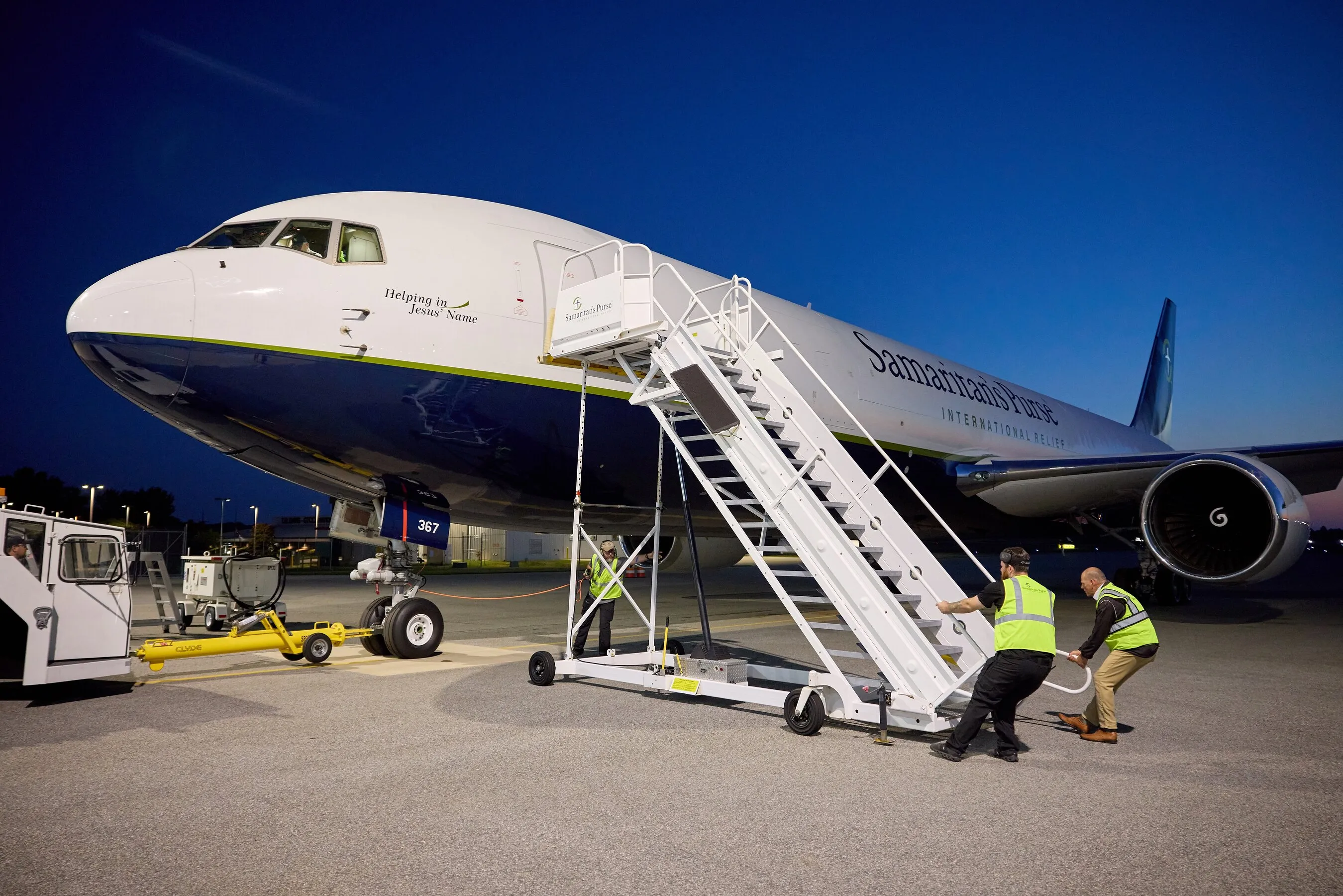 Samaritan’s Purse cargo plane on an airport tarmac with workers moving boarding stairs at night.
