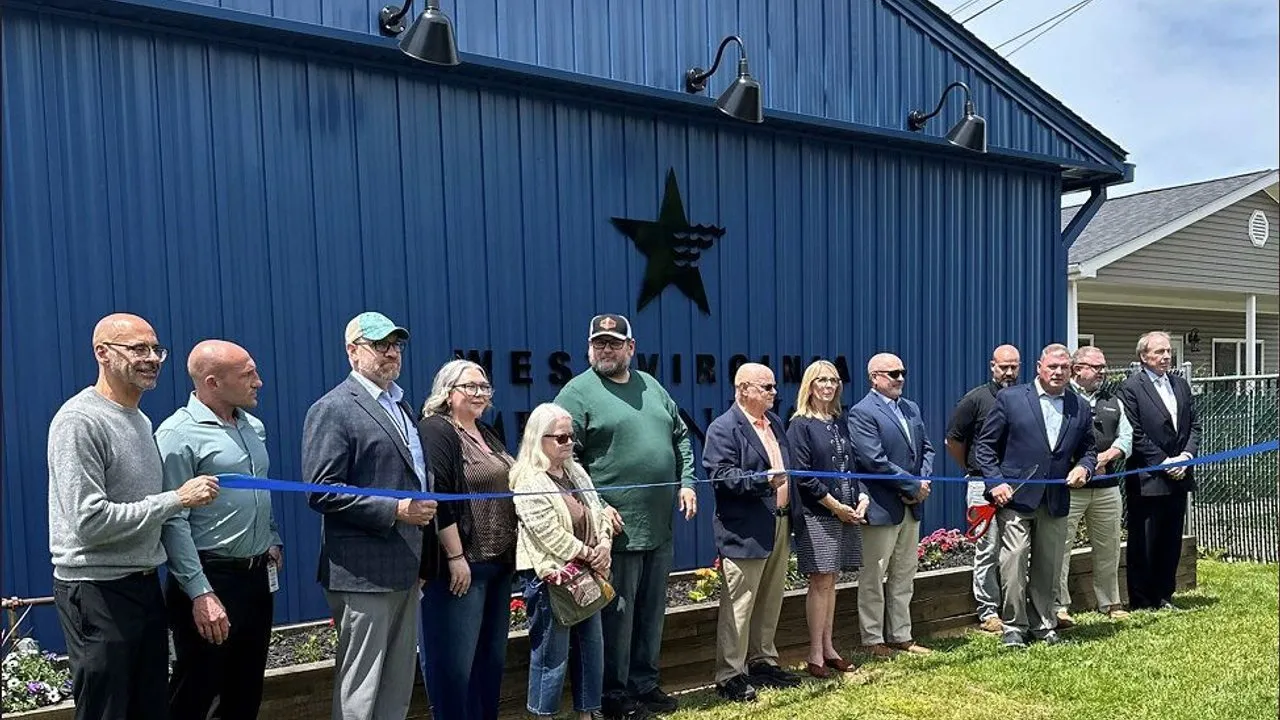 West Virginia American Water team members and board members, with Nitro city officials, hold a blue ribbon outside a blue West Virginia American Water building during a ribbon-cutting ceremony.