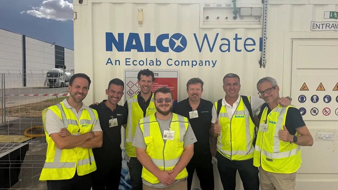 Seven workers in high-visibility vests stand outside a NALCO Water facility.