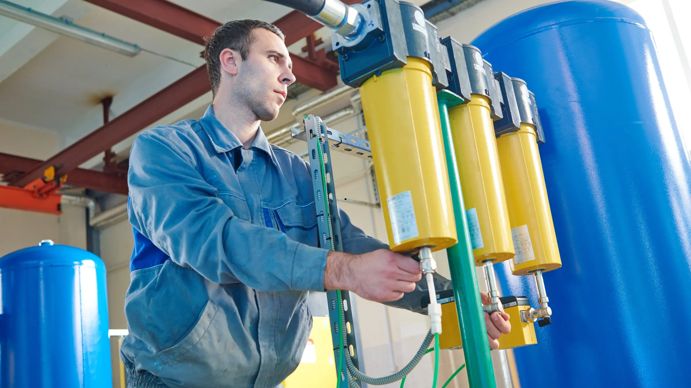A technician adjusting yellow filter housings on blue water purification tanks