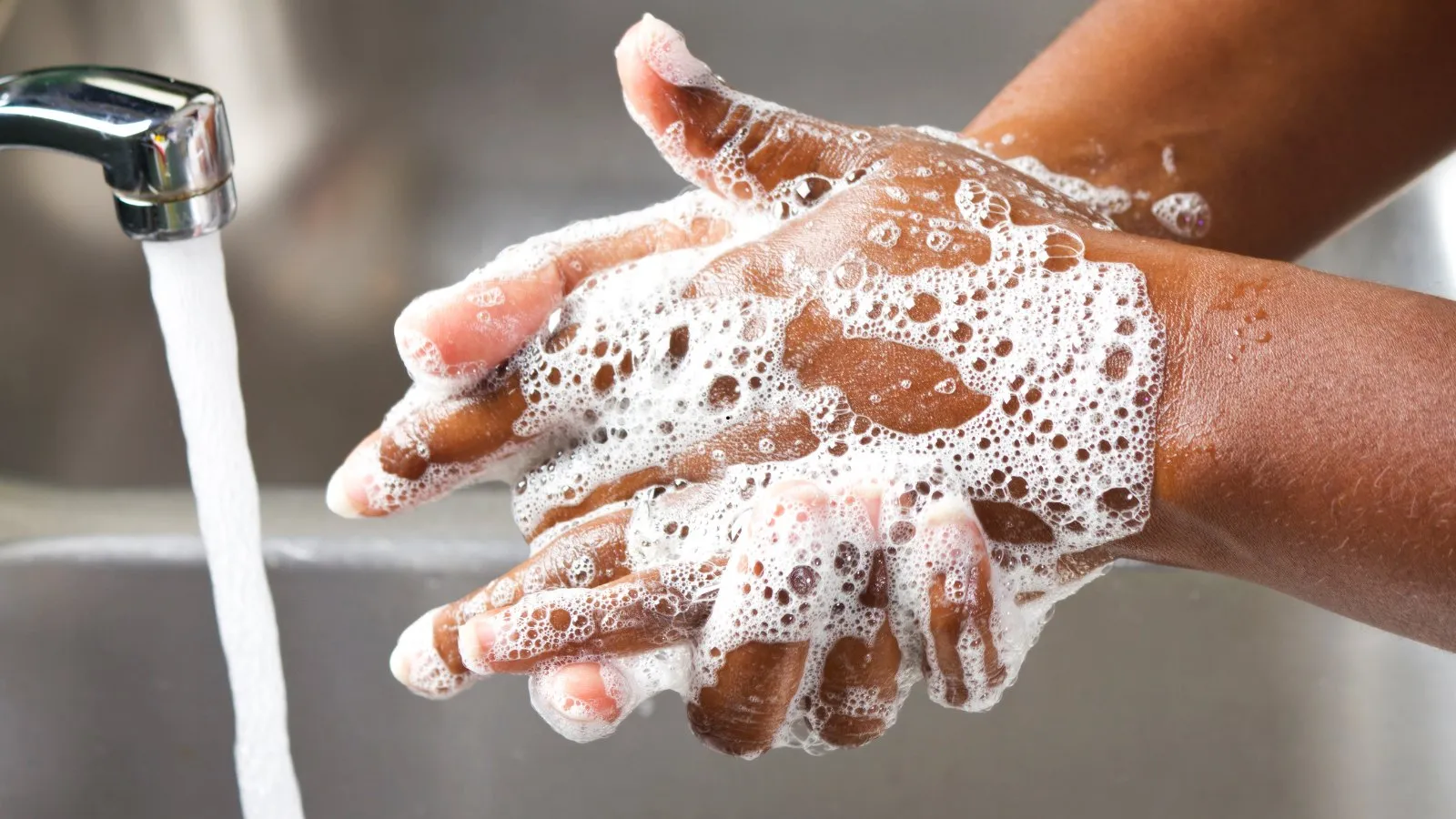 Hands lathered with soap under a running tap