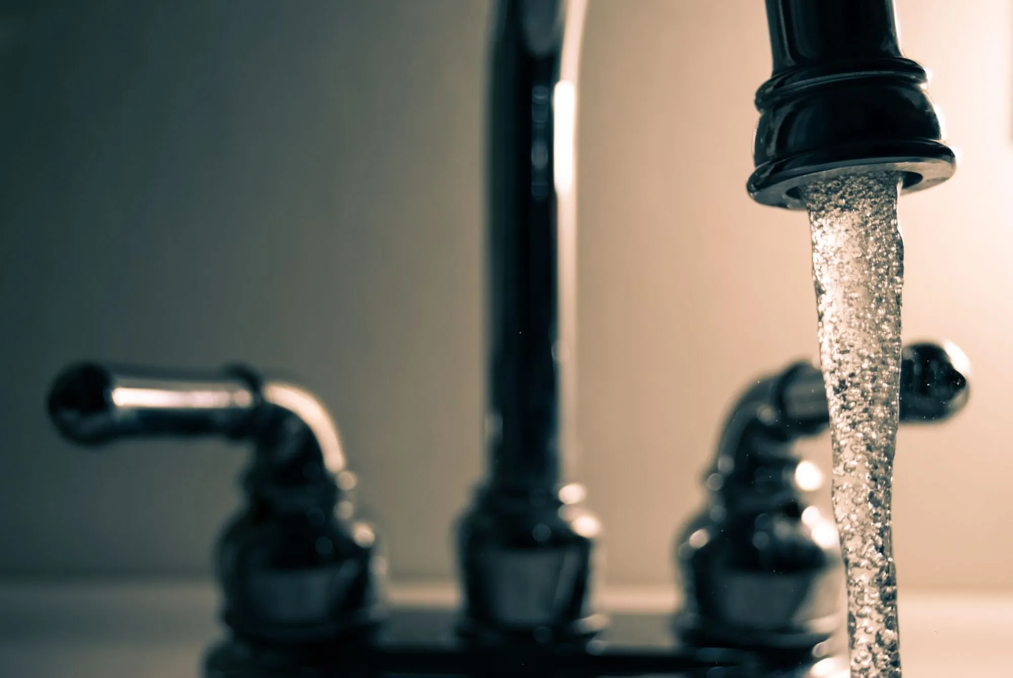 A clear stream of drinking water running from a steel tap