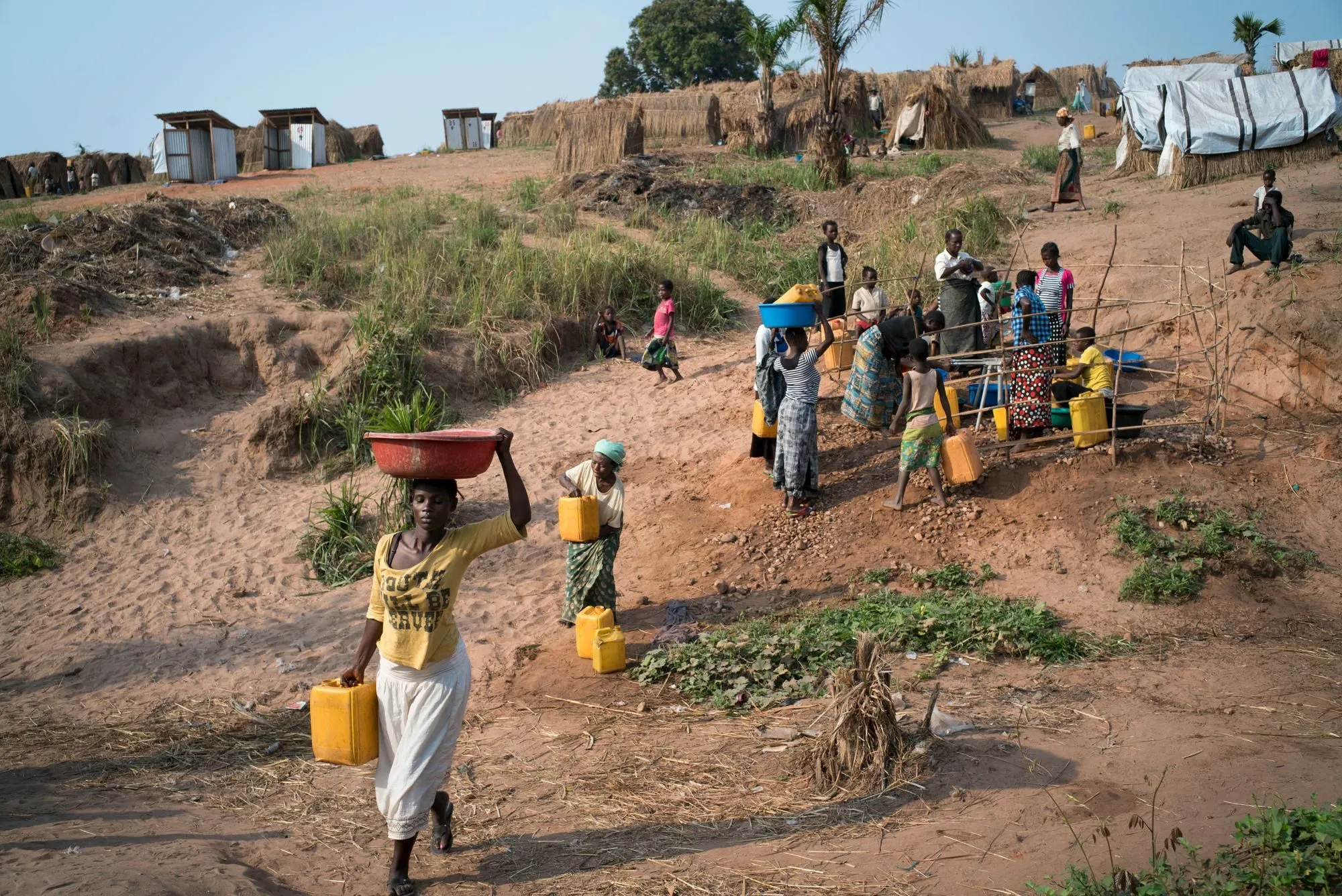 Villagers carry water in basins and jerrycans up a slope near Kalemie, DR Congo
