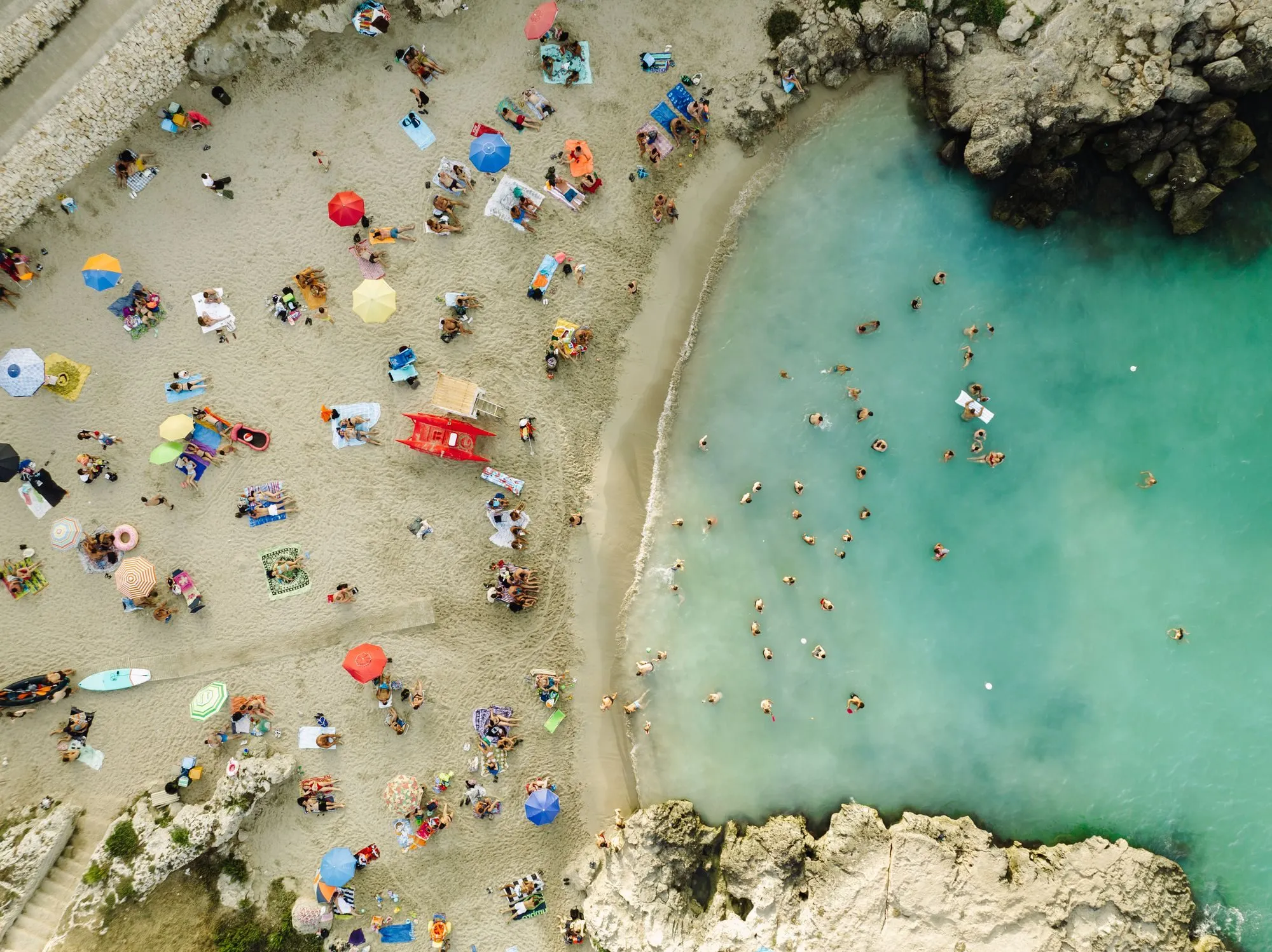 Swimmers and sunbathers on a beach at Monopoli, Italy, seen from above