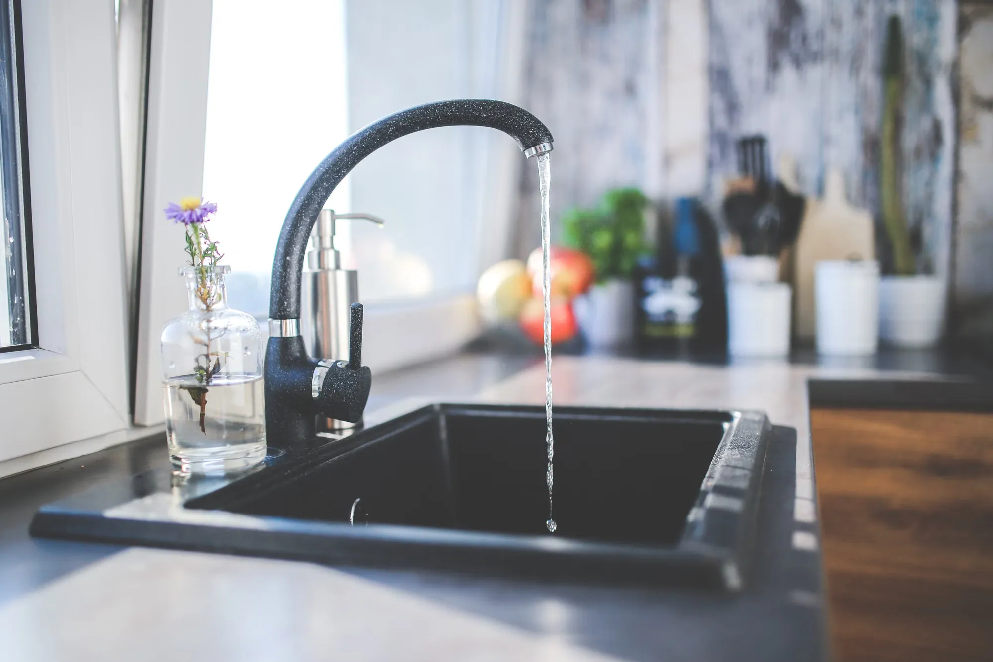 Water running from a kitchen tap into a black sink