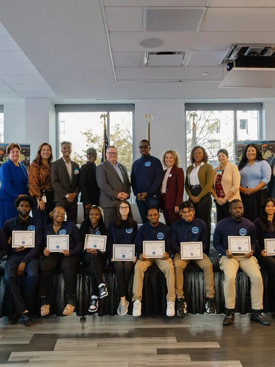 A group of people pose with certificates at an indoor recognition event.