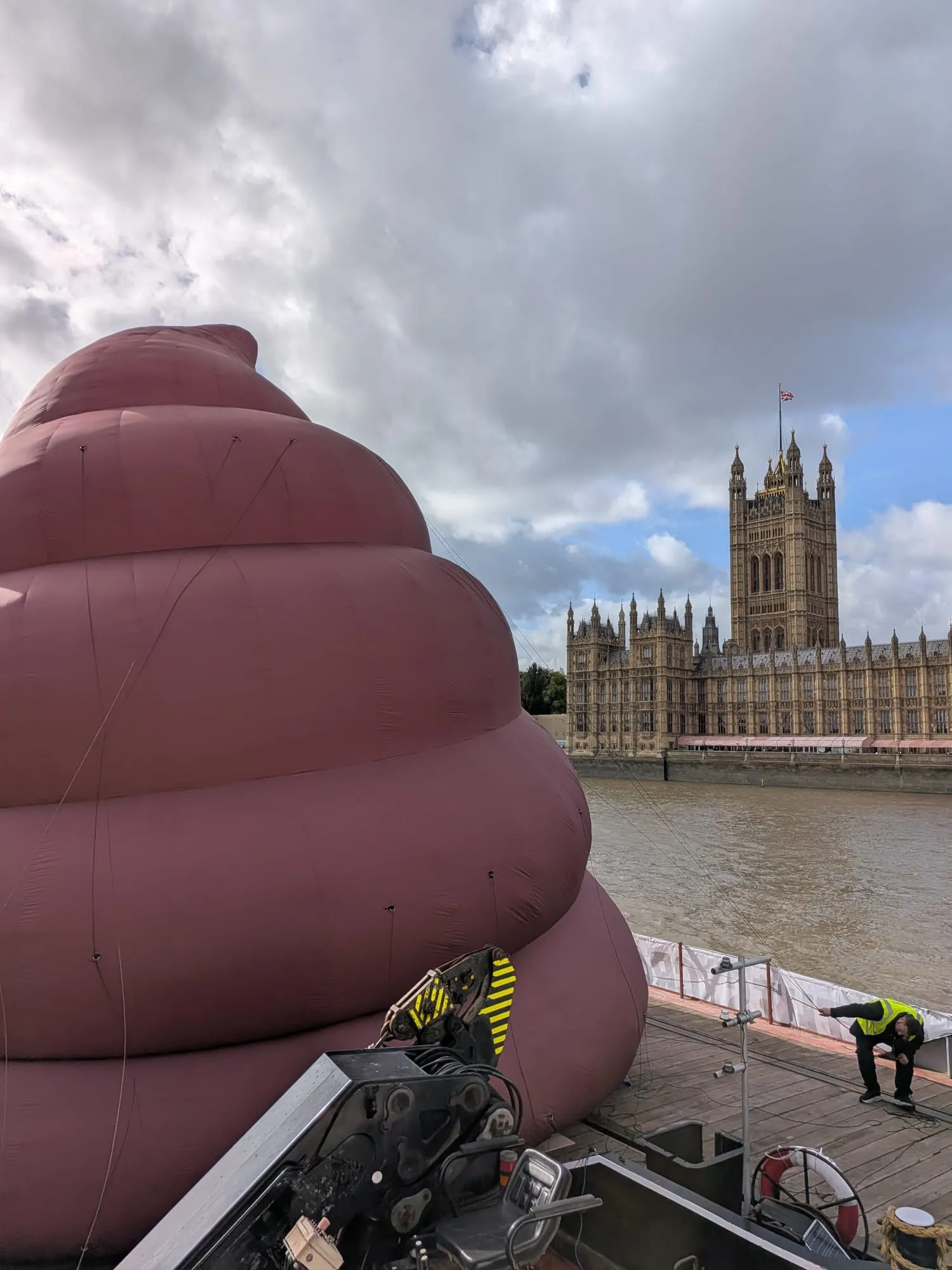 The brown inflatable sculpture fills a barge deck opposite the Palace of Westminster.