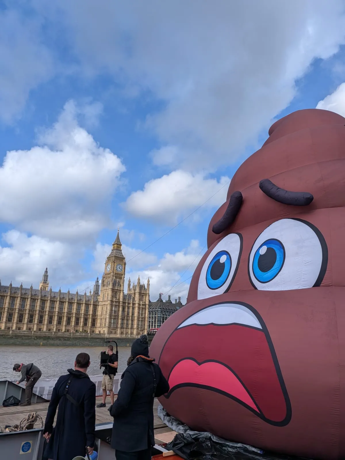 A brown inflatable sculpture with a face stands beside the Houses of Parliament and Big Ben.