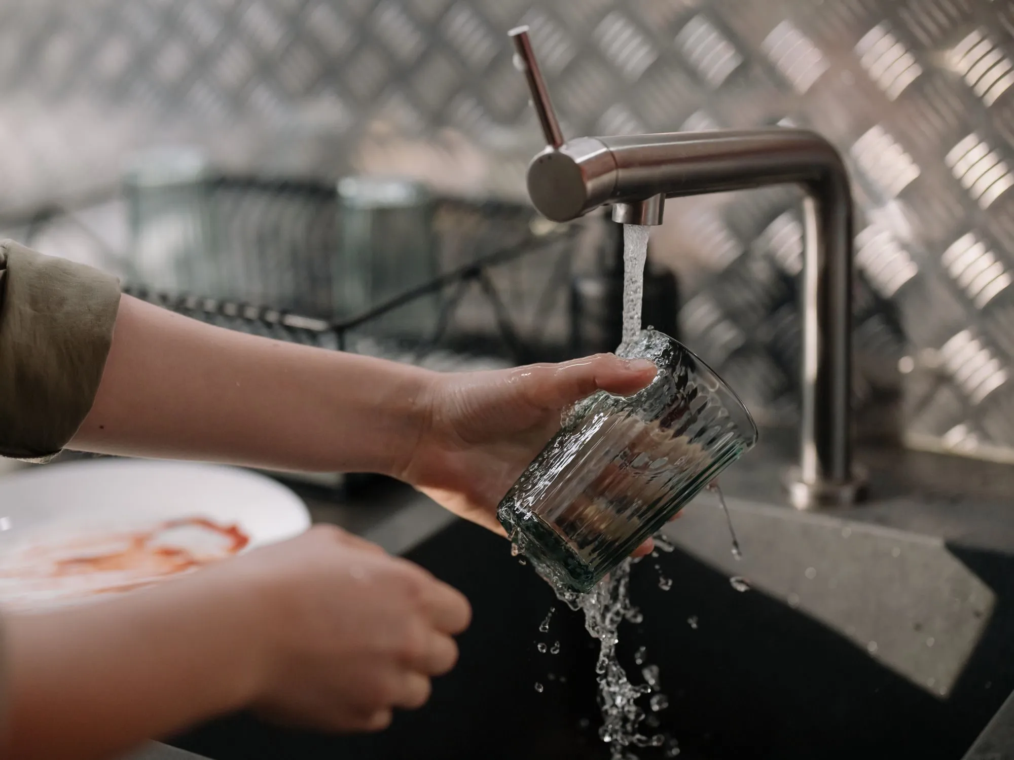 A glass held under a running kitchen tap