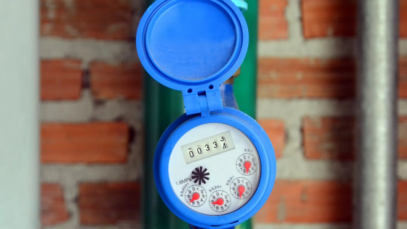 A blue domestic water meter on a brick wall