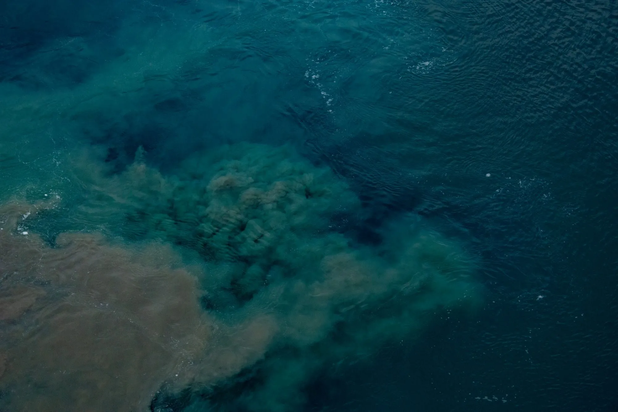 A cloud of pollution spreading through open water, seen from above
