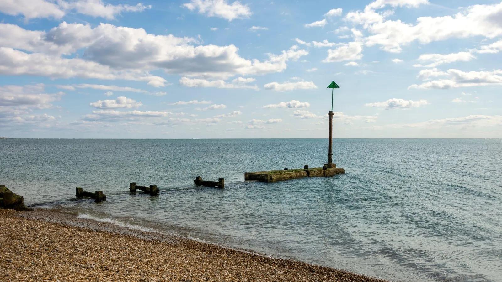 A sewage outfall pipe running out to sea from a shingle beach