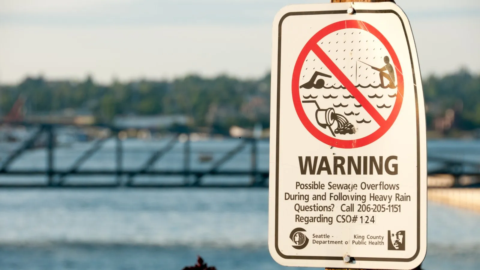 A sign by the water warning of possible sewage overflows during and after heavy rain