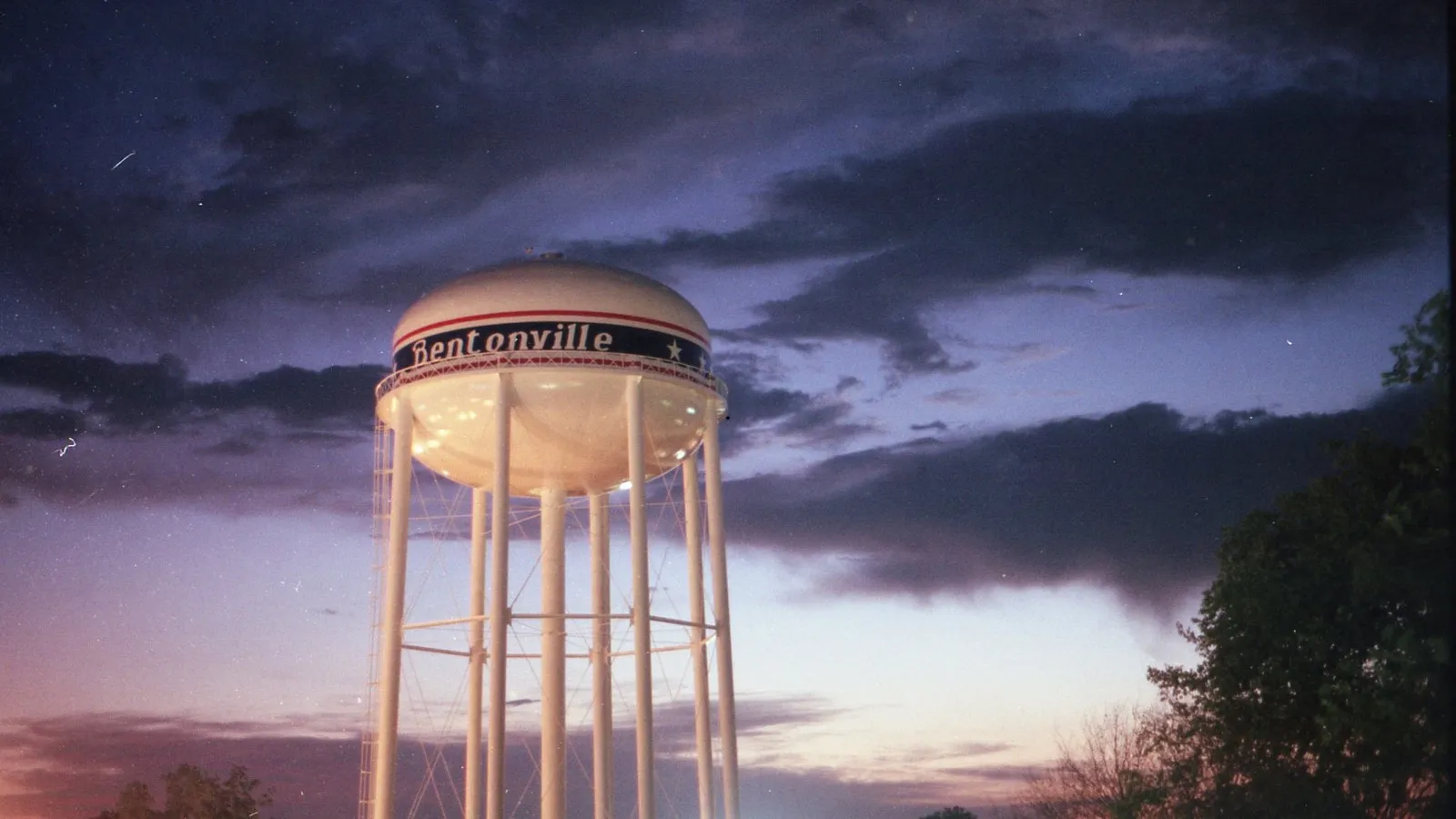 A town water tower on tall legs against an evening sky
