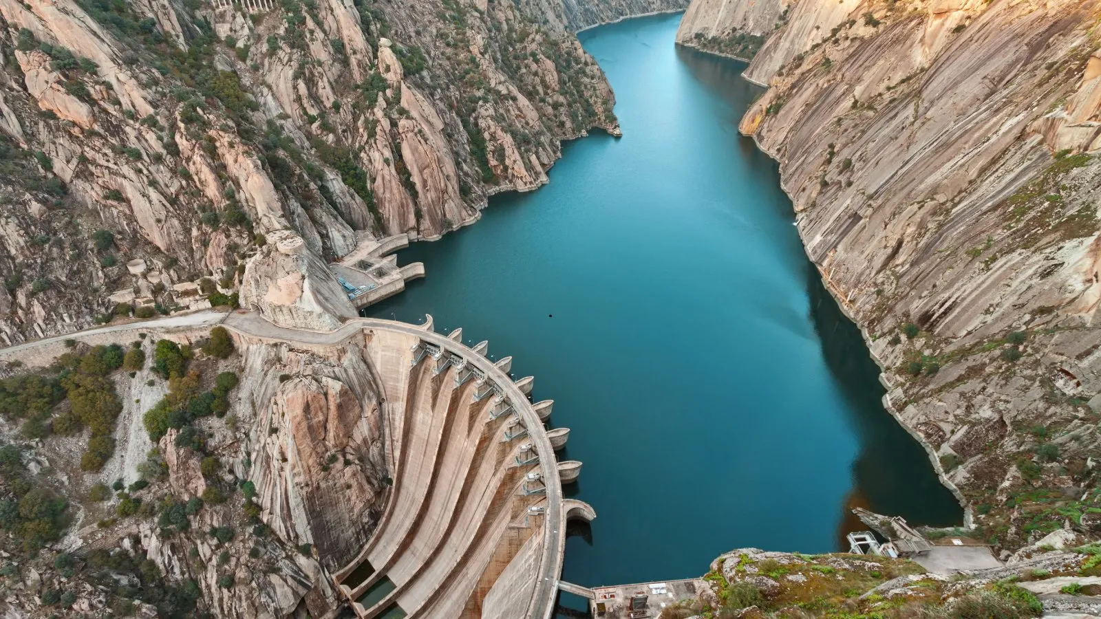 A concrete dam holding back a reservoir in a deep rocky gorge